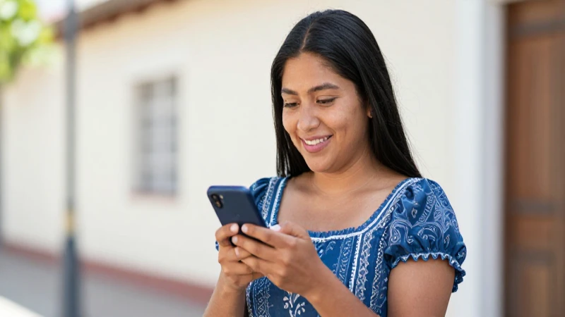 Mujer mexicana sonríe, sosteniendo un teléfono