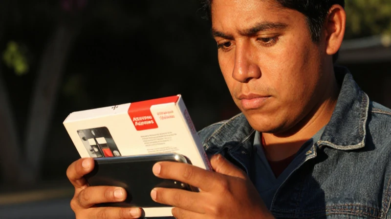 Mexicano con smartphone, desempaqueta productos AliExpress