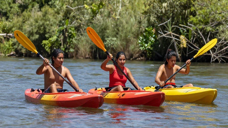 Tres amigos kayaking en un río soleado